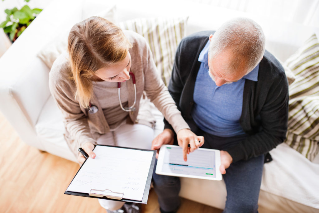 Vermittlungsagentur mit Tablet beim Gespräch mit Senior